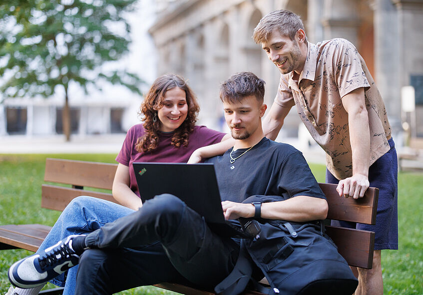 Three students watch a presentation on their laptop. 