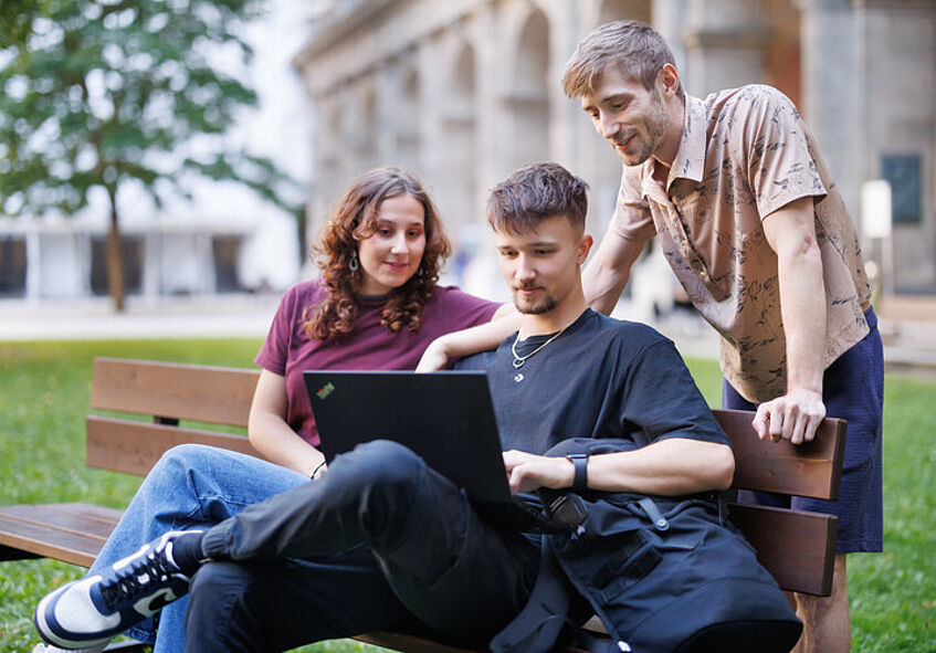 Studierende sitzen auf einer Bank im Arkardenhof