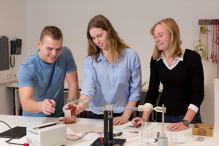 Three physics students conducting an experiment.