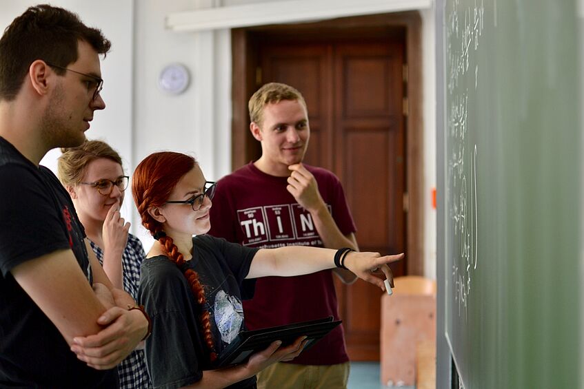 Studierende betrachten eine Tafel.