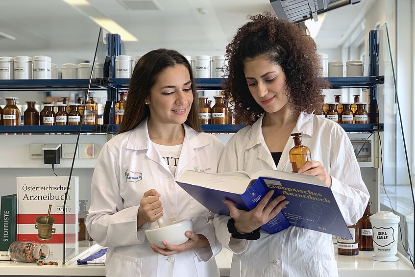 Two students are looking up something in a book in the laboratory.