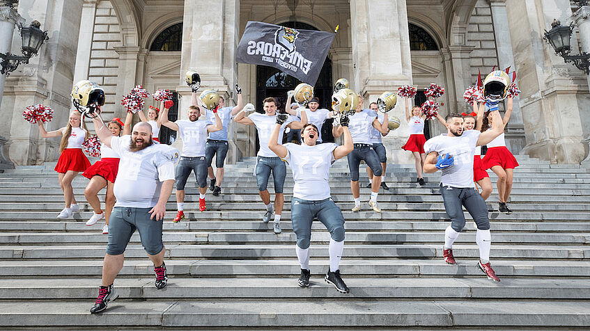 Footballspieler und Cheerleader auf der Treppe beim Eingang des Universitätshauptgebäudes